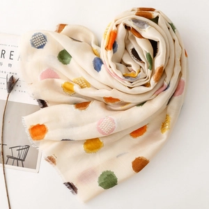 Détail de pois multicolores sur une écharpe en coton et lin beige à franges