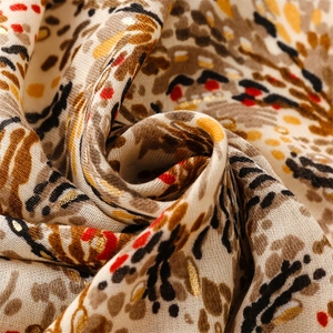 Detail macro shot of cotton linen scarf featuring gold foil wheat patterns and soft draping