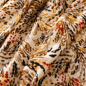 Detail of warm beige scarf with satin gold stamping and artistic wheat wave pattern