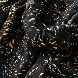 Detailed close-up of soft black scarf fabric featuring gold foil and colorful speckle print