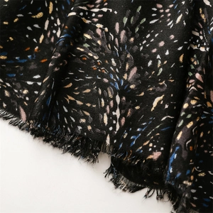 Macro detail of black fabric with multi-color abstract spots and natural fringe edges