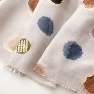 Gros plan sur une écharpe grise douce avec pois colorés et détails dorés élégants