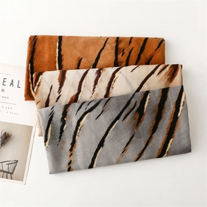 Close-up of zebra pattern scarves in orange, white, and blue with gold foil gradient details