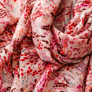 Macro detail of pink scarf fabric with gold foil wheat patterns and soft woven texture