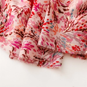 Detail of pink cotton scarf with red abstract print and sparkling gold foil patterns