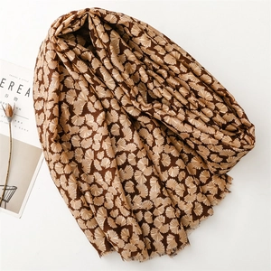 Detail of dark brown linen-feel scarf with silver gingko leaf print and frayed edges