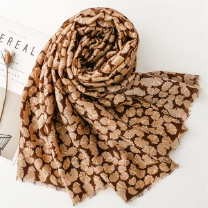 Detail of soft brown cotton scarf with silver ginkgo leaf pattern and frayed edges