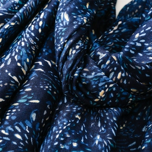 Detail of dark blue scarf with gold foil wheat patterns and soft knit texture