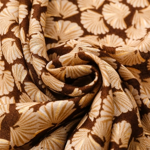 Macro detail of scarf fabric showing golden ginkgo leaf pattern and soft woven texture
