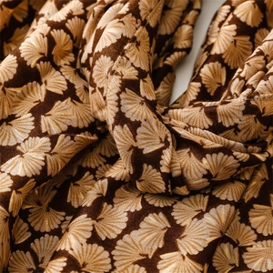 Macro shot of ginkgo leaf jacquard pattern on a warm brown scarf fabric with gold accents