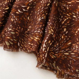Detailed macro view of brown scarf fabric with floral pattern and fringe edge finish