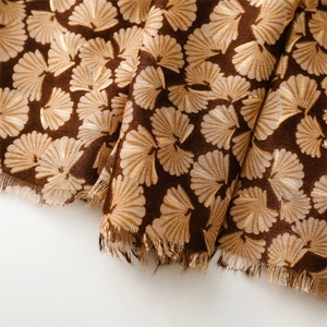 Close-up of brown cotton linen scarf featuring metallic gold ginkgo leaf patterns