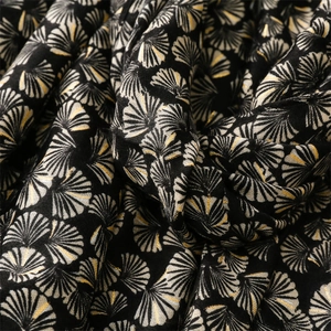 Macro view of woven ginkgo leaf pattern with golden metallic threads on a black shawl
