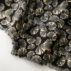 Detail of black cotton linen scarf featuring golden ginkgo leaf pattern and fringe edges