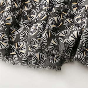 Detailed view of grey scarf featuring golden ginkgo leaf foil print and fringed edges