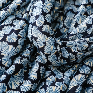 Detailed view of navy blue scarf with golden ginkgo leaf prints and soft satin texture