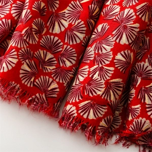 Detail of red scarf with gold fan jacquard pattern and soft fringe edges