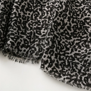 Macro detail of leopard print scarf fabric showing premium gray pattern and fringed edges