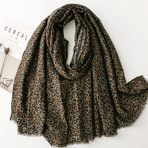 Macro detail of dark green leopard print scarf fabric with fine fringed edges and soft texture