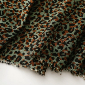 Close-up of soft woven fabric with classic leopard print and fringe details on the edge