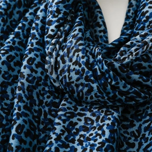 Close-up of blue leopard print scarf fabric showing detailed texture and soft knit weave