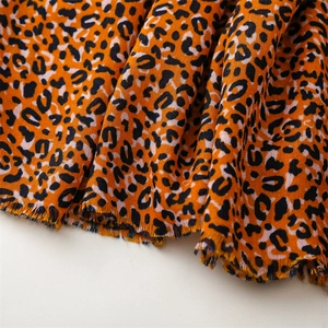 Detailed close-up of leopard print cotton-linen scarf with orange base and frayed edges