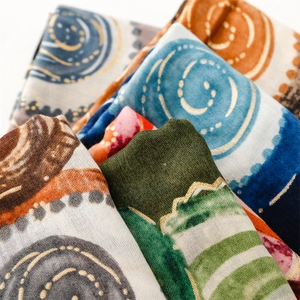 Detail of printed scarves with metallic gold leaf patterns and diverse artistic colors