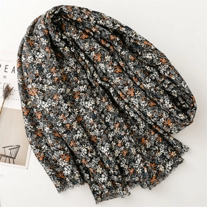 Detailed macro of black cotton-linen scarf with floral daisy pattern and fringe edges