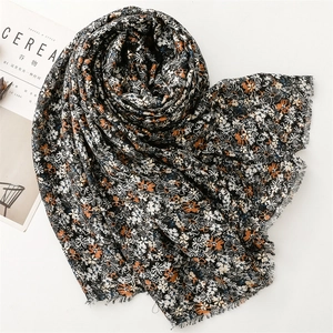 Flat lay of floral cotton linen scarf with small flower print and fringed edges on white background