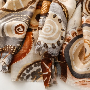 Detail of bohemian cotton-linen scarf with golden geometric prints and frayed edges