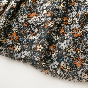 Detail of floral linen-feel scarf featuring gold foil flower prints and fringe edges