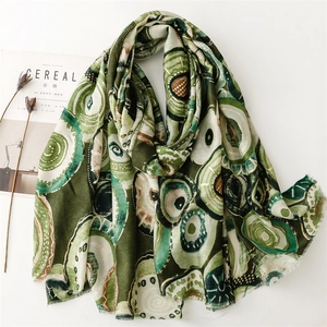 Detailed texture of green cotton-linen scarf with golden geometric prints and frayed edges