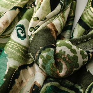 Detail of artistic green landscape print scarf featuring premium gold foil outlines