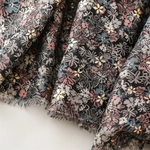 Close-up of floral fabric featuring gold foil flower prints and frayed edge details