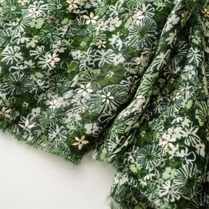Close-up of cotton-linen scarf featuring floral prints and gold foil accents with frayed edges