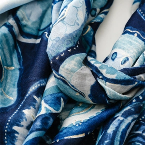 Close-up of blue cotton linen scarf with golden bubble patterns and abstract wave texture