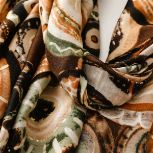 Detail of bohemian scarf showing geometric patterns with golden accents and linen texture