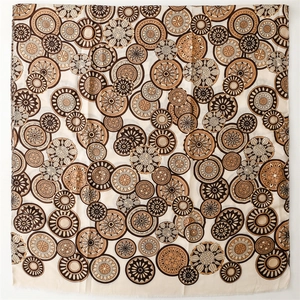 Close-up of golden mandala geometric pattern on brown linen-feel scarf with raw edges