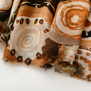 Detail of warm-toned scarf featuring golden foil geometric patterns and soft frayed edges