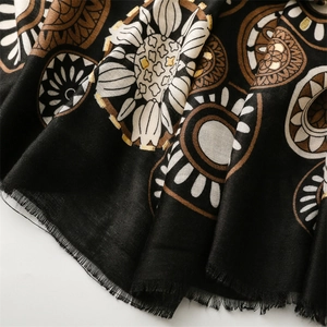 Detail of bohemian scarf showing gold foil sun patterns and frayed edges on cotton fabric