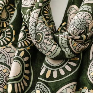 Detail of dark green scarf showing gold mandala patterns and cotton linen texture