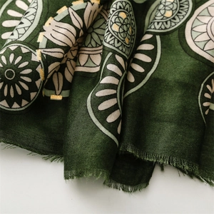 Detail of dark green cotton scarf with gold foil floral pattern and fringe edges