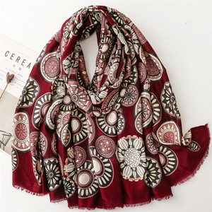 Detail of burgundy linen-feel scarf featuring golden wheel patterns and boho fringes