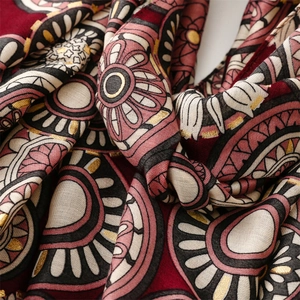 Detail of gold foil wheel pattern on burgundy cotton-linen feel scarf with shimmer finish