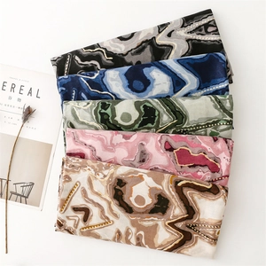 Détail de foulards effet coton et lin avec imprimés ondulés dorés en cinq couleurs variées