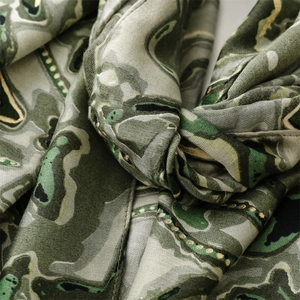 Gros plan sur les motifs dorés d'une écharpe en coton-lin vert olive et gris pour femme