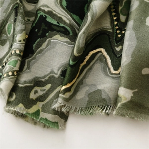 Détail de l'écharpe motif marbre vert forêt avec lignes dorées et bords à franges fins