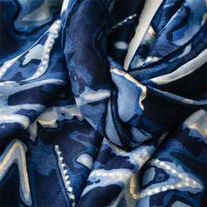Gros plan d'une écharpe bleu foncé effet lin avec dorure et motif marbré fluide