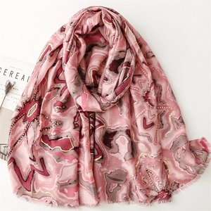 Détail de l'écharpe en coton et lin rose avec motifs floraux dorés et bords effilochés