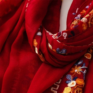 Detailed close-up of vibrant red scarf featuring exquisite floral ethnic embroidery